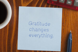 Top view of gratitude changes everything written note on the wooden desk with pen aside.