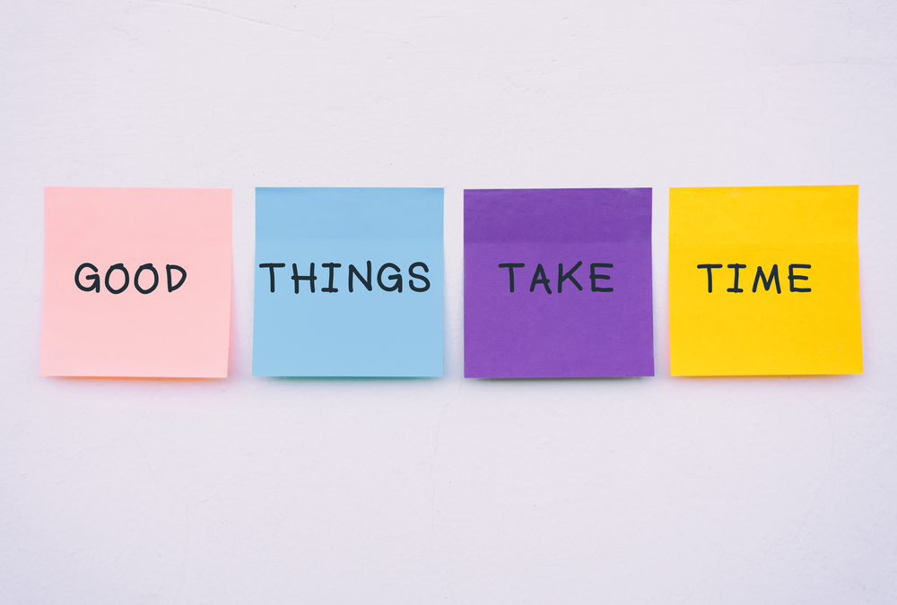 Good things take time quote on colorful sticky paper on a wall, pastel colors.