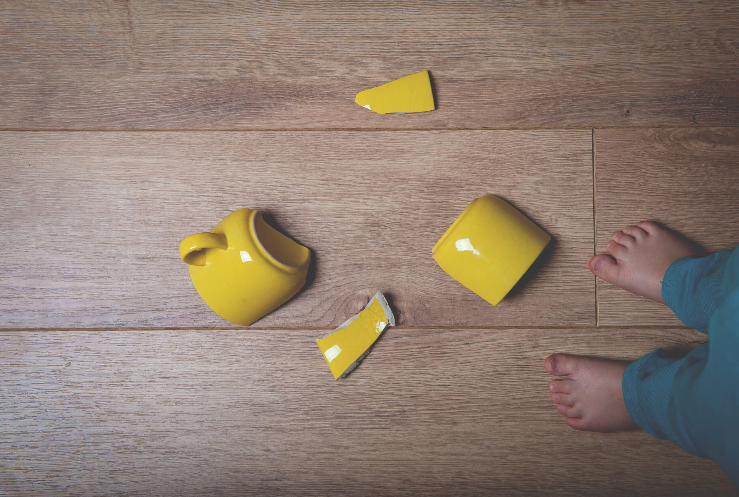 Broken yellow cup on the floor.