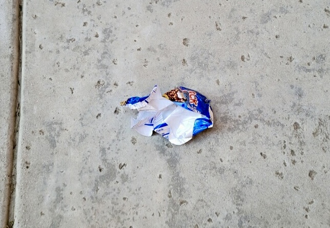 Crumbled candy wrapper on the ground.